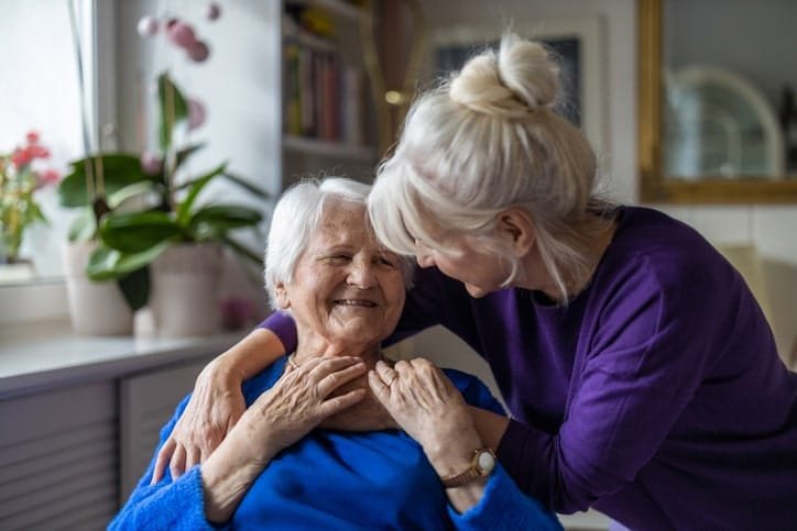 Woman hugging her elderly mother living in a memory care facility